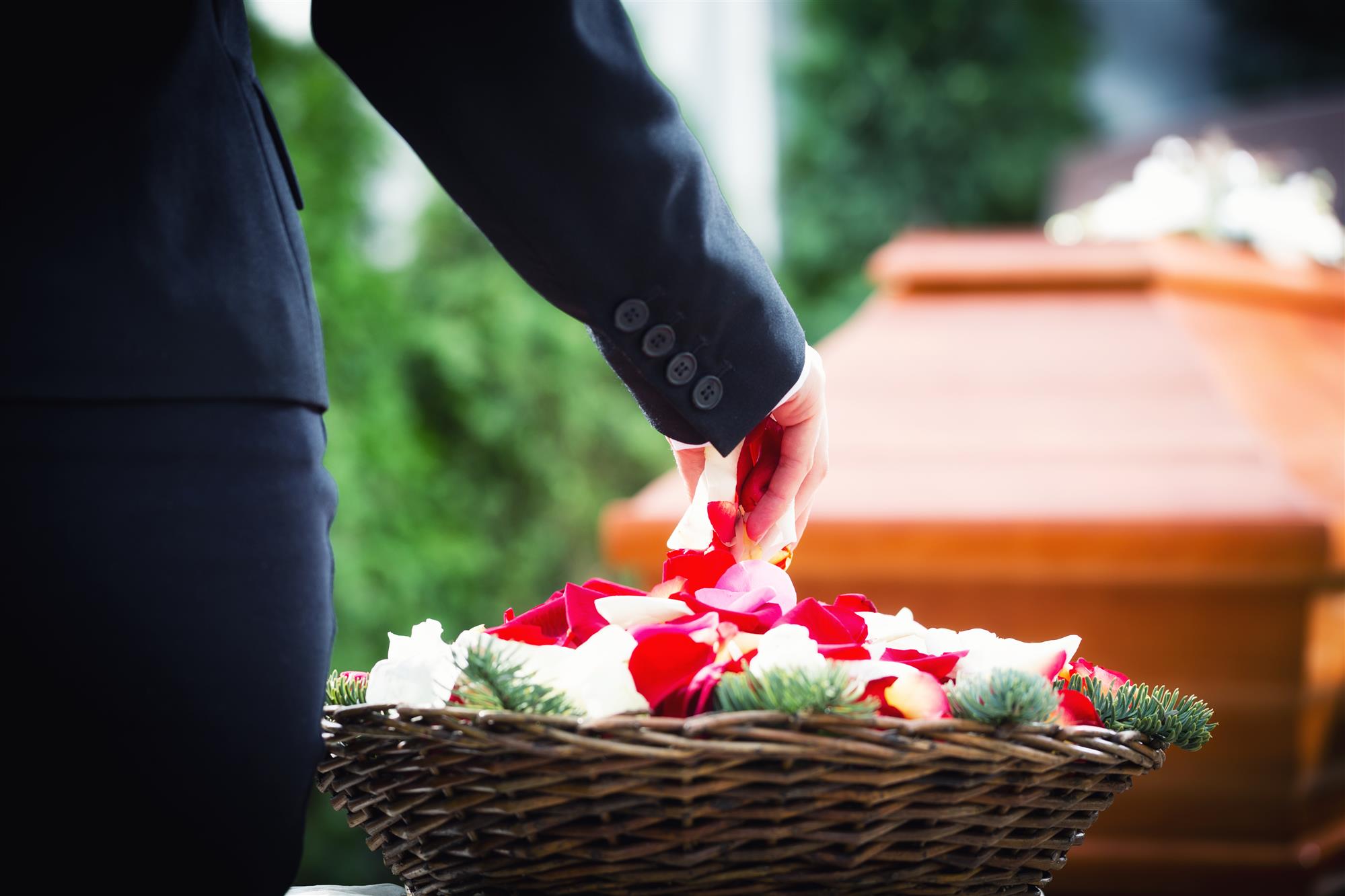 funeral putting rose petals on coffin