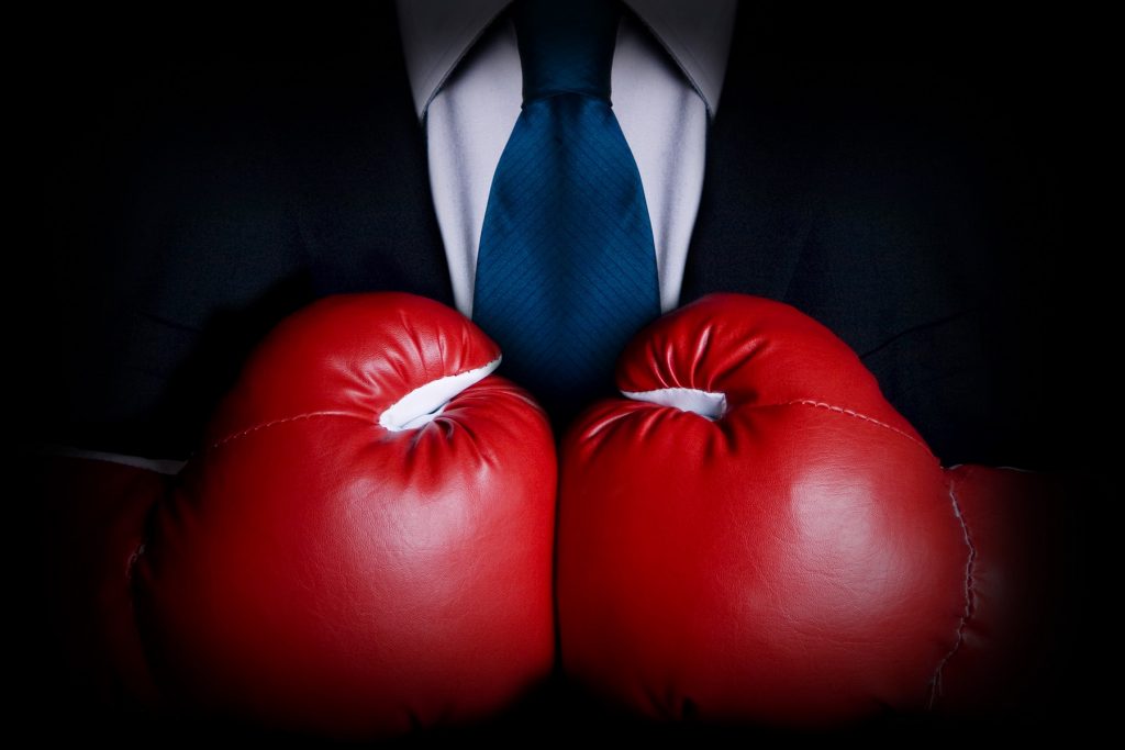 Stock image of person wearing business suit and boxing gloves