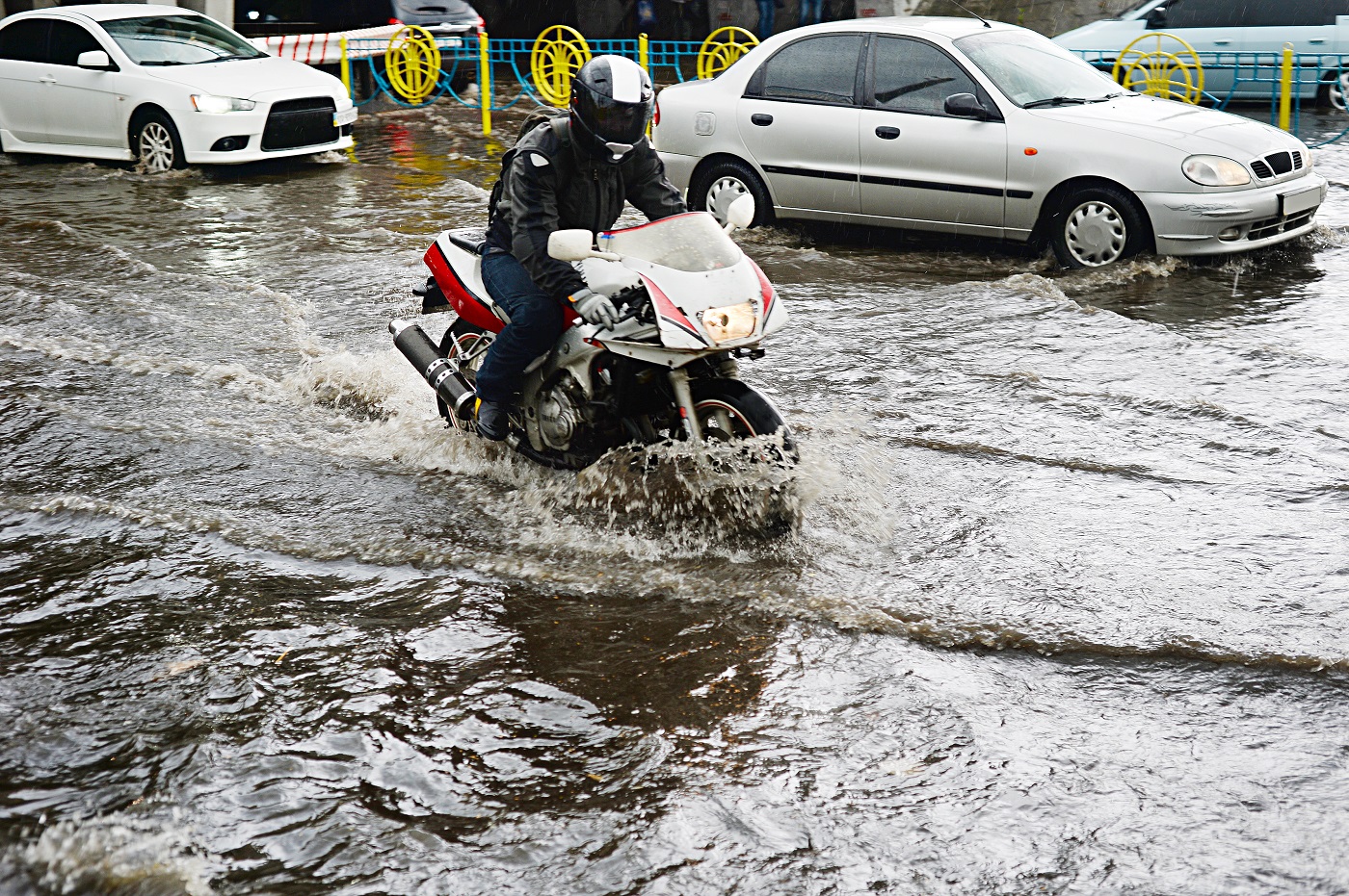 Motorcycle and cars on flooded road during the heavy rain