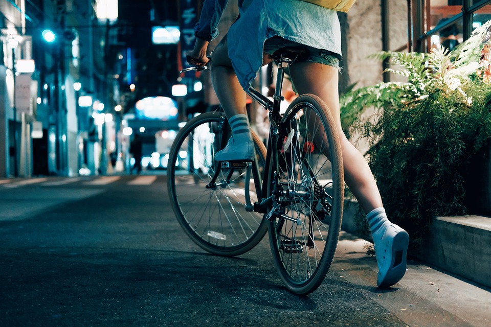 young woman biking in the city at night